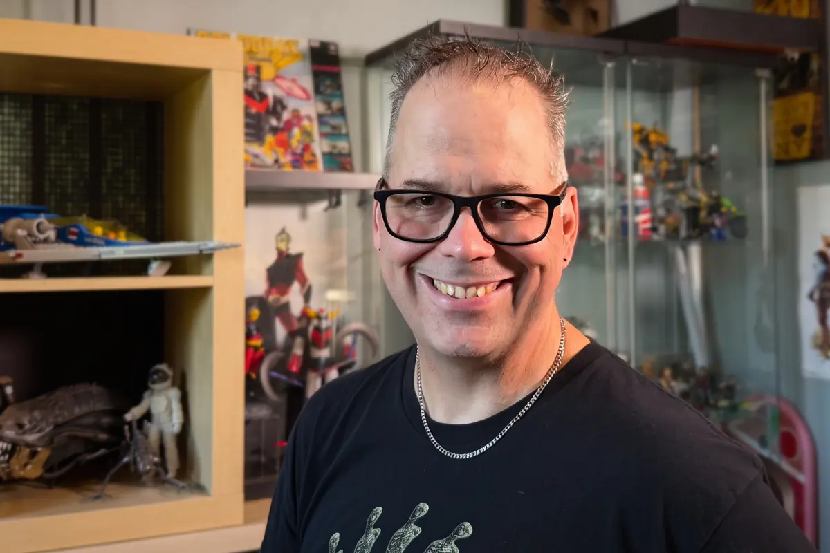 François Paradis in front of the display cases in his collection workshop, figurines and science-fiction items behind him.